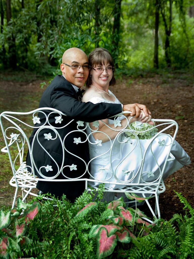 Photo Of Groom And Bride Looking Behind Them At The Camera At Garden Wedding Venue